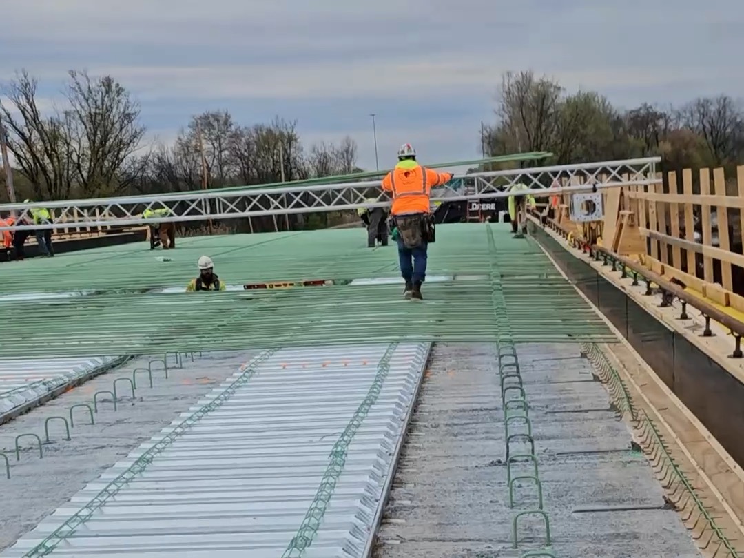 Construction crew using the rebar roller to move rebar across a bridge deck